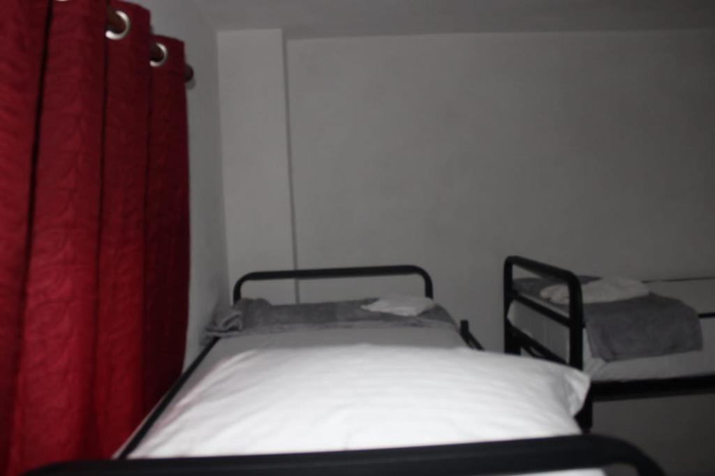 a bed in a room with a red curtain at Crew Hostel Tirana in Tirana