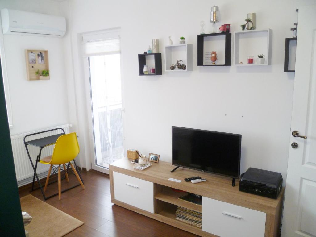 a living room with a television and a yellow chair at Munteniei - The Sunset Studio in Hunedoara