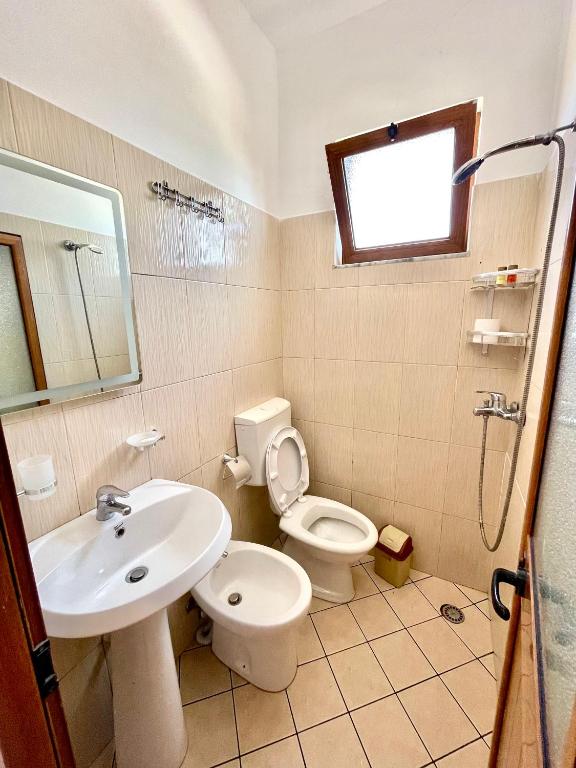 Un baño con lavabo, inodoro y ducha. en Xhou's Home, en Shkodër