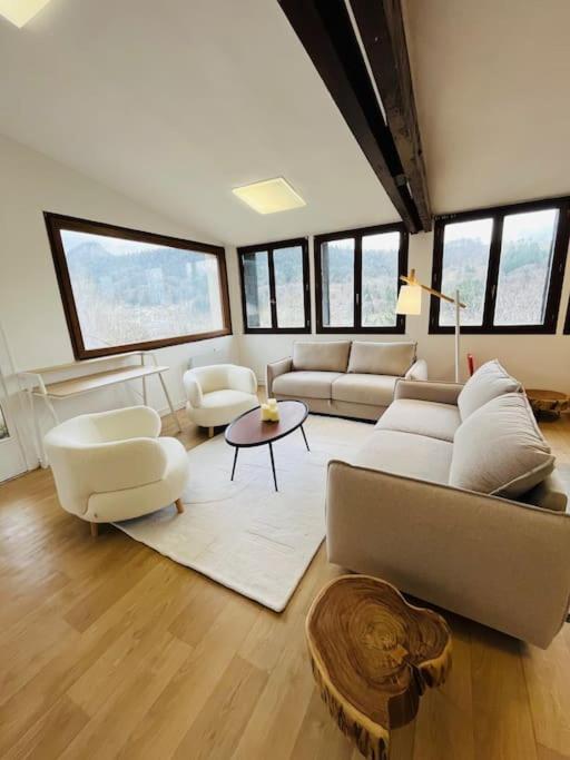 a living room with a couch and chairs and windows at Appartement Le Romy Vue Montagne in Mont-Dore
