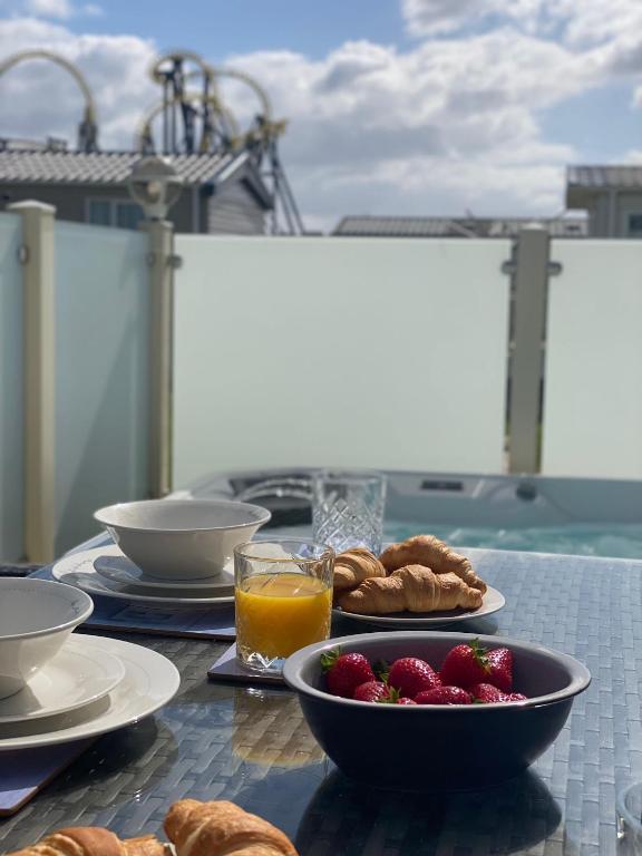 a table with a bowl of strawberries and a bowl of orange juice at Premium accommodation with luxury HOT-TUB and decking area, near Fantasy Island in Ingoldmells