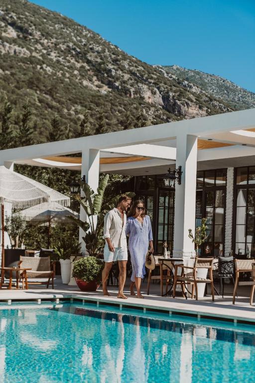a man and a woman standing next to a swimming pool at Ölüdeniz Blu Luxury Unique Hotel - Adults-Only in Oludeniz