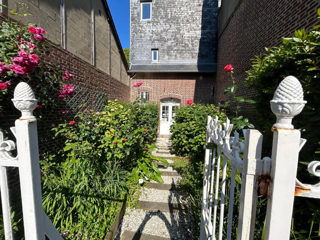 une clôture blanche devant une maison fleurie dans l'établissement Ma jolie maison de Pont l'Evêque, à Pont-l'Évêque
