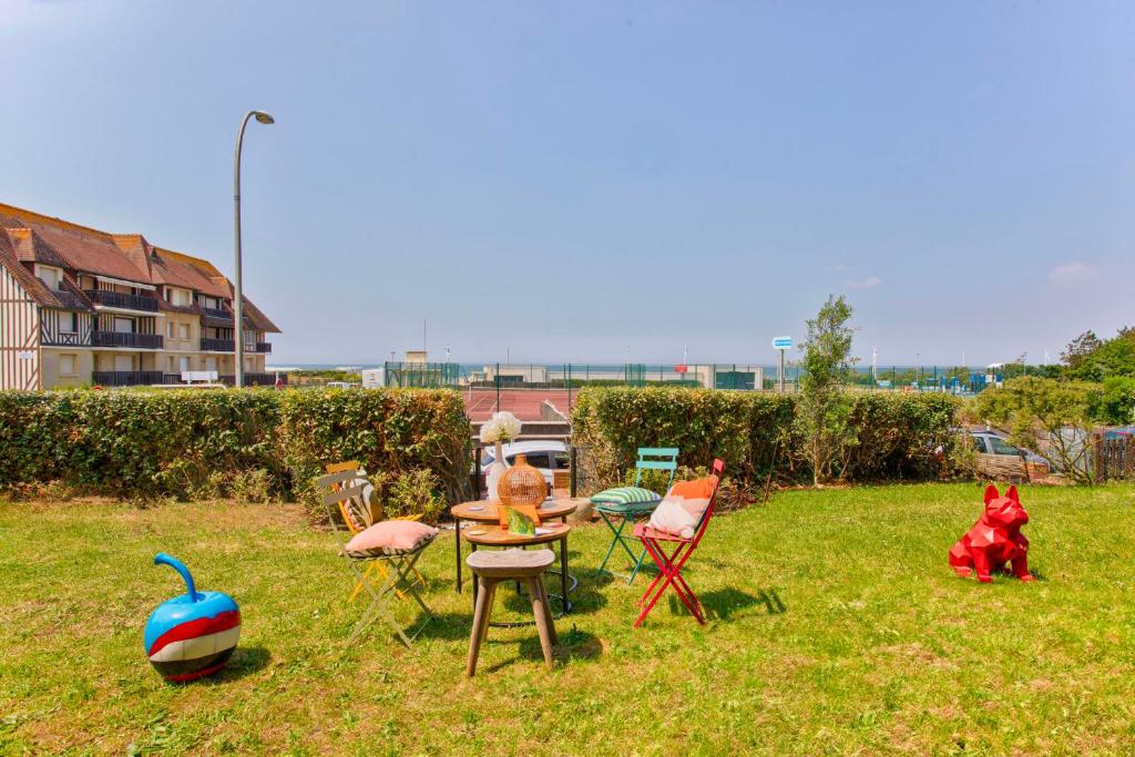 un groupe de chaises et une table dans l'herbe dans l'établissement Les Terrasses - Vue Mer - Tourgéville, à Tourgéville
