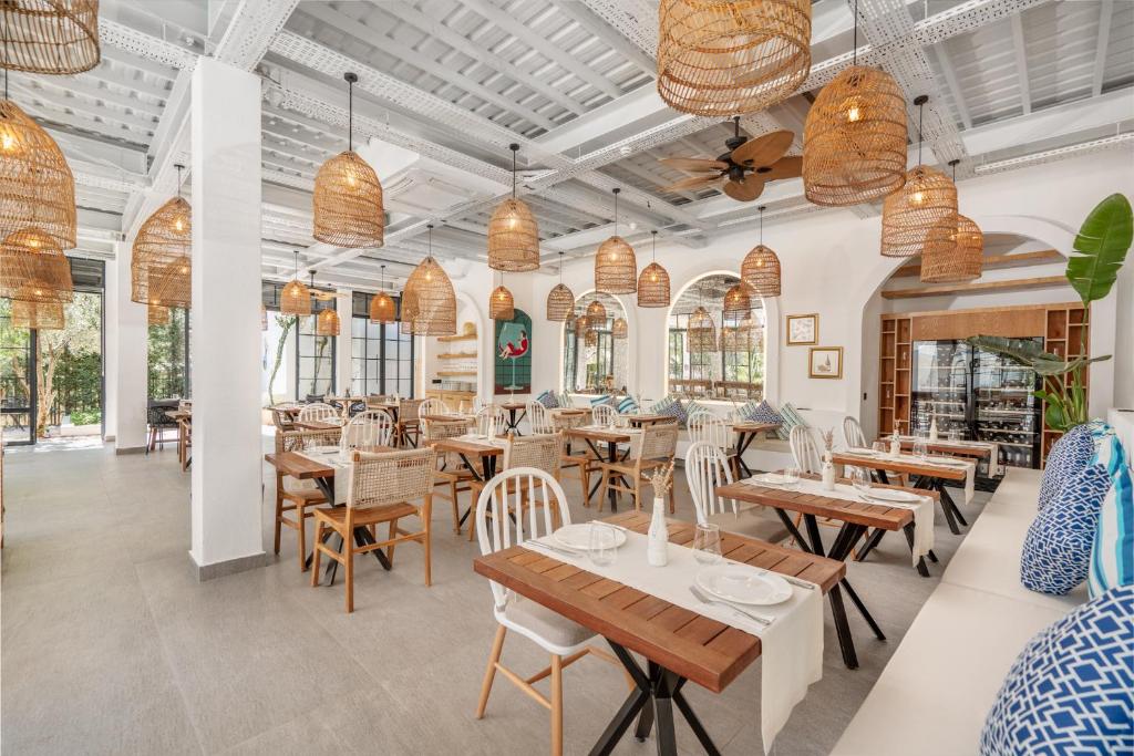a restaurant with tables and chairs and pendant lights at Ölüdeniz Blu Luxury Unique Hotel - Adults-Only in Oludeniz