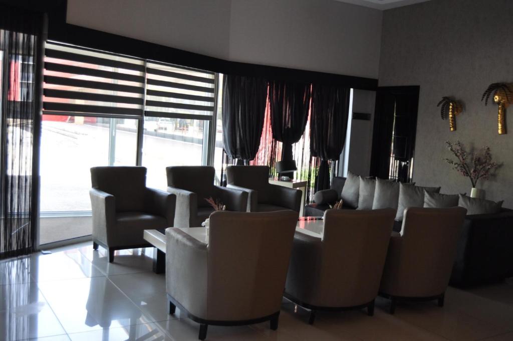 a waiting room with chairs and tables and windows at Orty Airport Hotel in Izmir