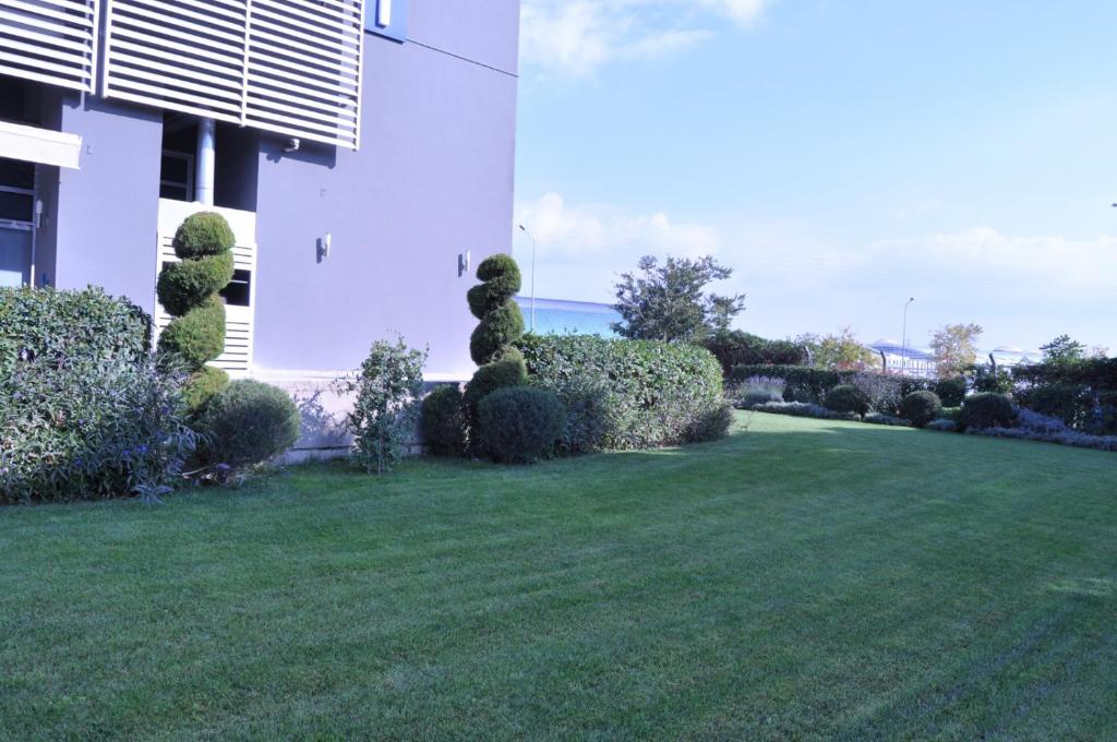 a green yard with bushes and a building at Orty Airport Hotel in Izmir