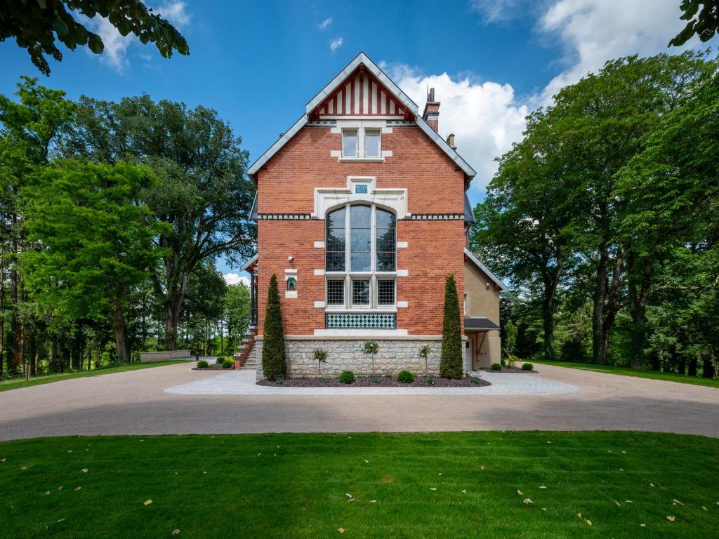 una casa in mattoni con una grande finestra sul vialetto di Cottage de Montchamp a Châtenay