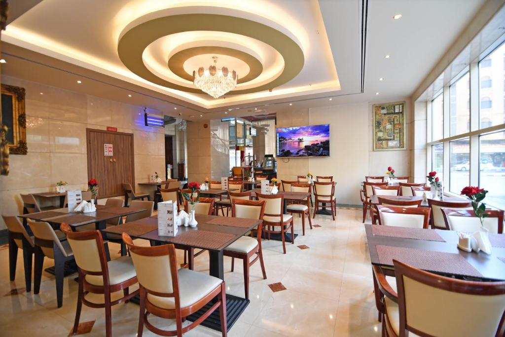a restaurant with tables and chairs and a chandelier at Nejoum Al Emarat in Sharjah