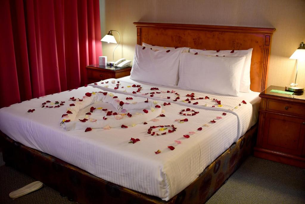a bed with red rose petals on it at Nejoum Al Emarat in Sharjah