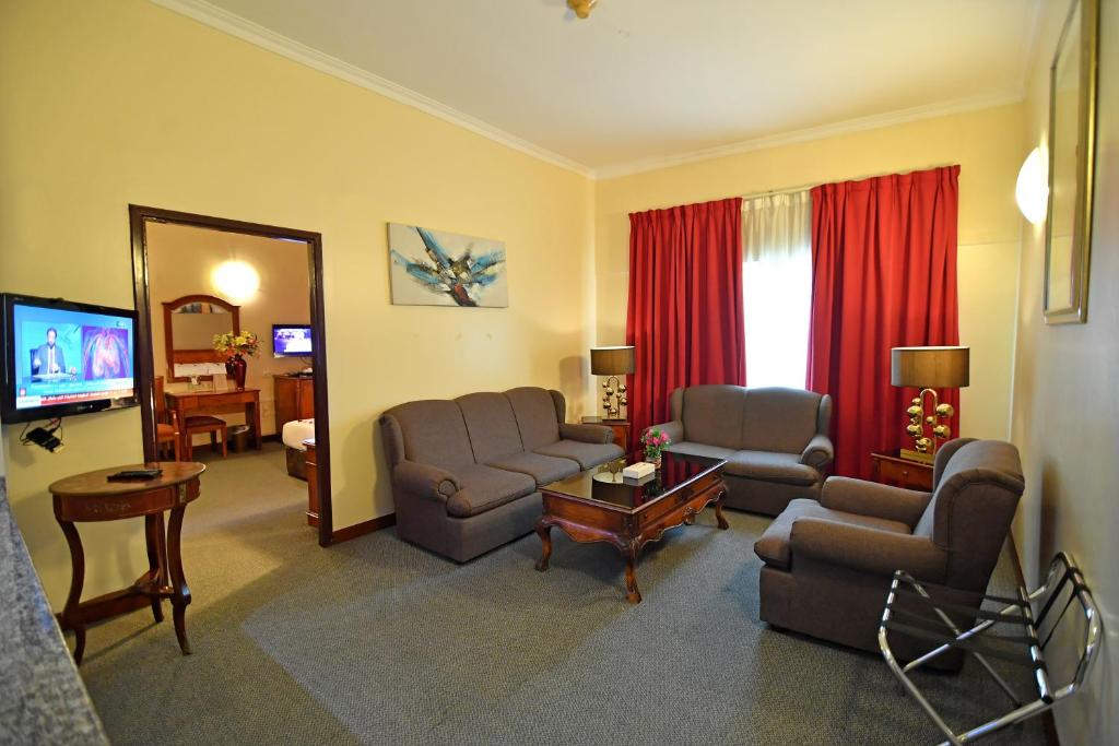 a living room with a couch and chairs and a television at Nejoum Al Emarat in Sharjah