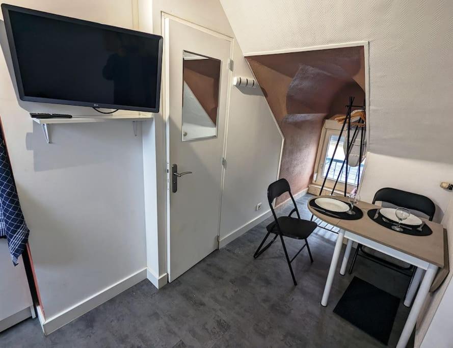 Il comprend un salon doté d'une télévision et d'une table avec des chaises. dans l'établissement Studio calme - Proche Zénith, à Caen