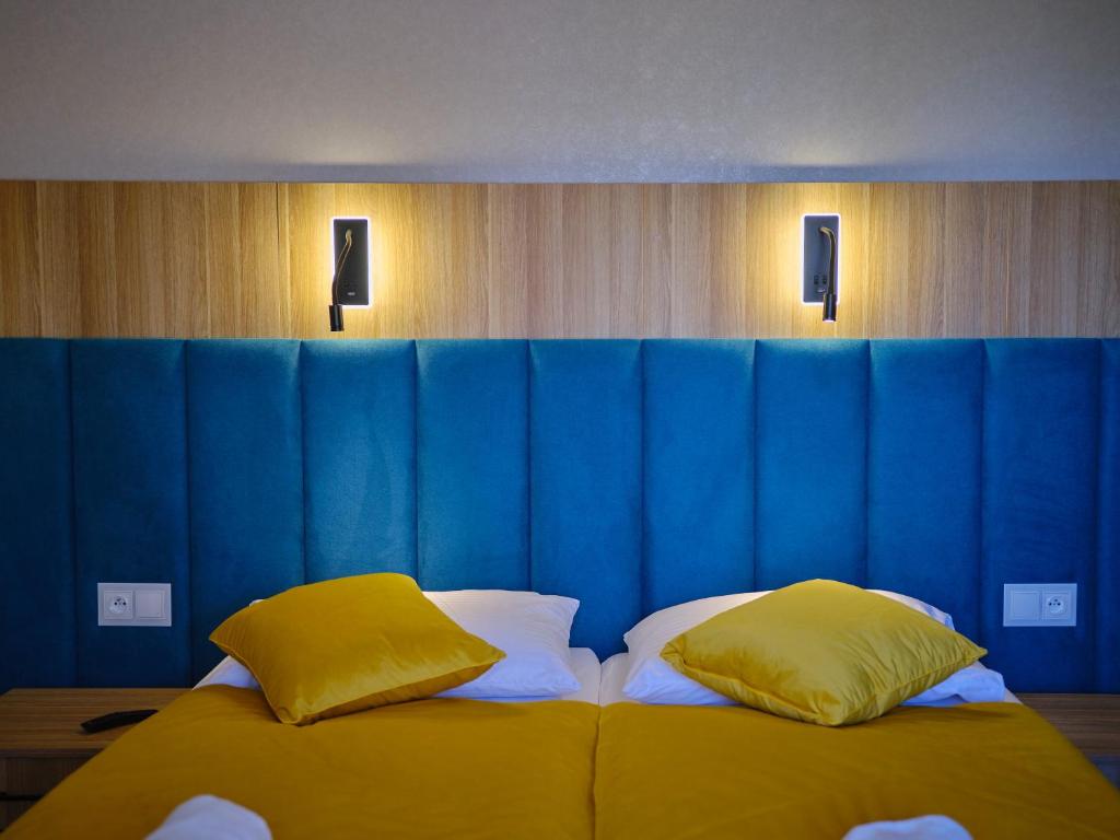 Close-up of teal padded headboard with illuminated reading lights and yellow accent pillows.