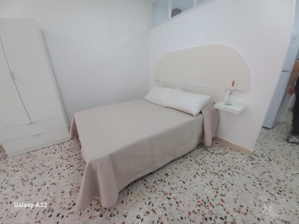 a small white bedroom with a bed and a mirror at Apartamento Paris in Alicante