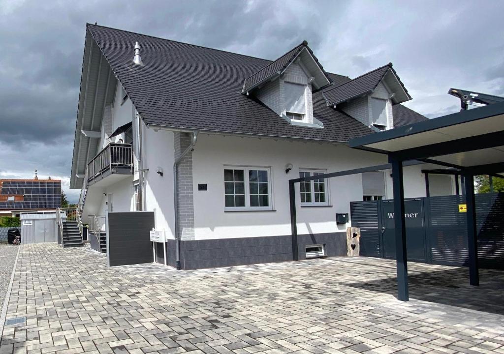 une maison blanche avec un toit noir et une allée en briques dans l'établissement Marianna Apartments Weimer, à Rust