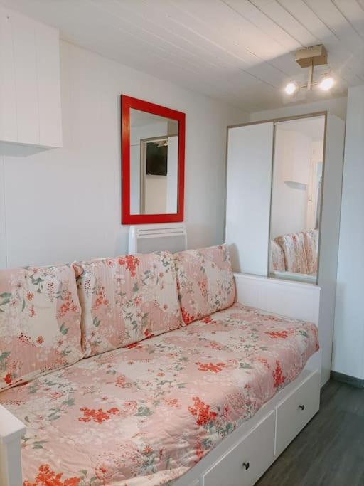 une pièce blanche avec un canapé avec des fleurs dessus dans l'établissement Studio fonctionnel au calme, à Franqueville-Saint-Pierre