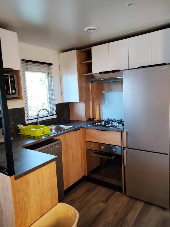 une cuisine avec des armoires en bois et des appareils en acier inoxydable dans l'établissement Mobil Home Les Charmettes 321, aux Mathes