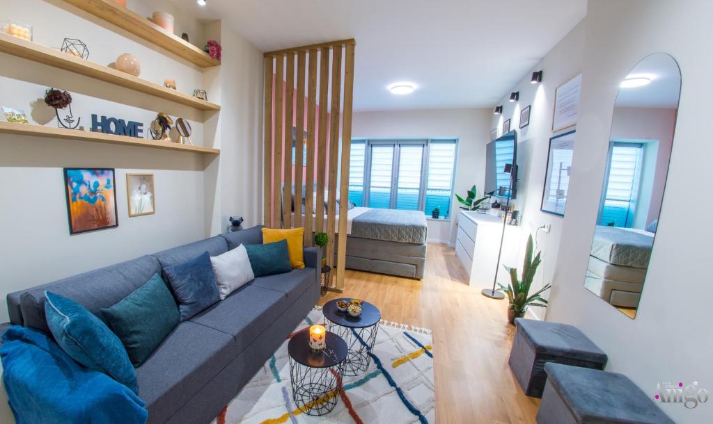 a living room with a blue couch and a bedroom at Iris Studio Apartment in Mostar