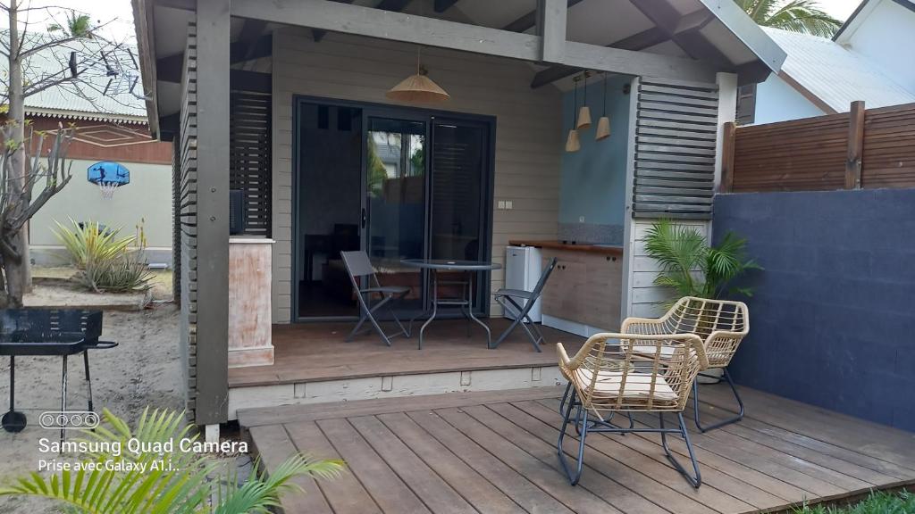 een houten terras met stoelen en een tafel erop bij Le latanier bleu in La Saline les Bains