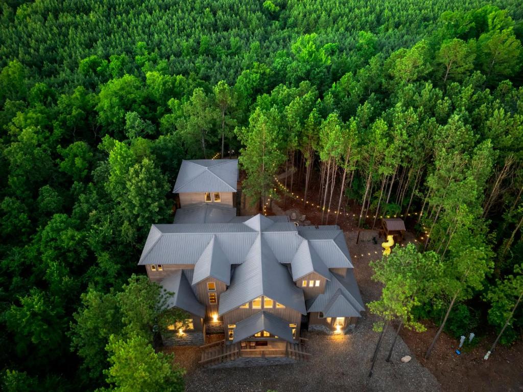 an aerial view of a house in the middle of a forest at Pet friendly family cabin with firepit creek outdoor kitchen playset & more in Broken Bow