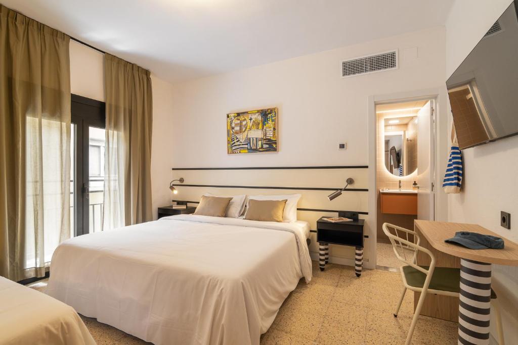 a hotel room with a large white bed and a desk at Hotel Robson - Smart Hotel in Lloret de Mar