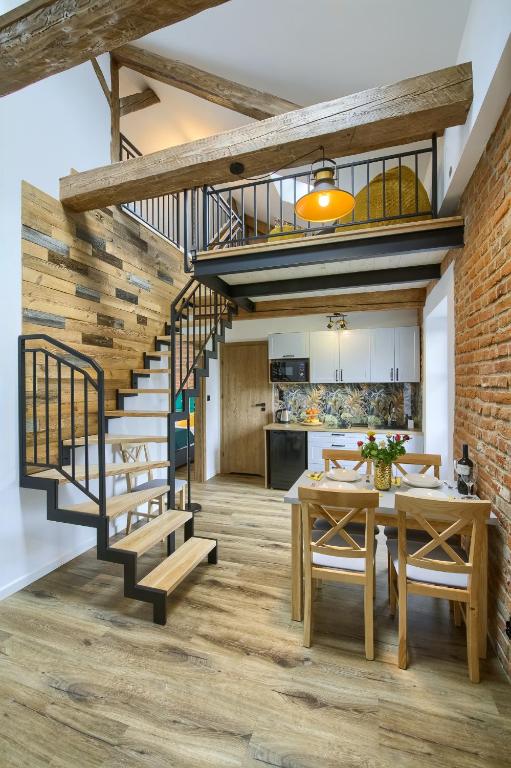 a kitchen and dining room with a staircase and a dining table at Apartamenty Pod Bocianem in Muszyna