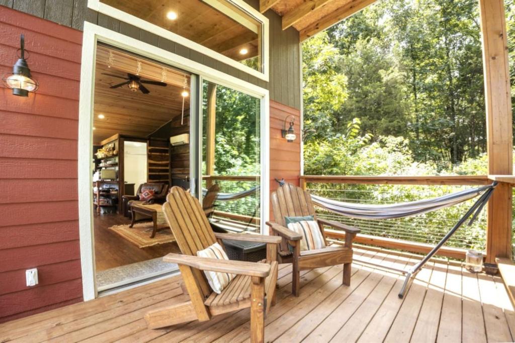 Un porche con dos sillas y una hamaca. en PIKES PEAK - Tiny Houses Of French Village, en French Village