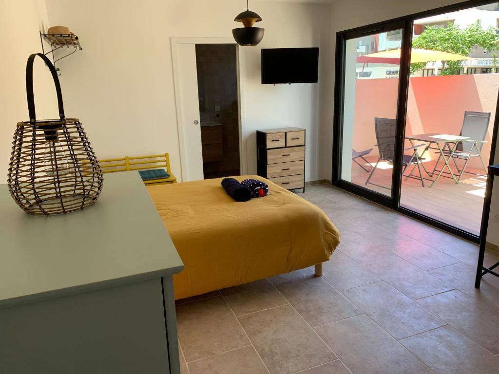Cet appartement comprend une chambre avec un lit et une cuisine avec une terrasse. dans l'établissement Studio la salicorne, à Sérignan