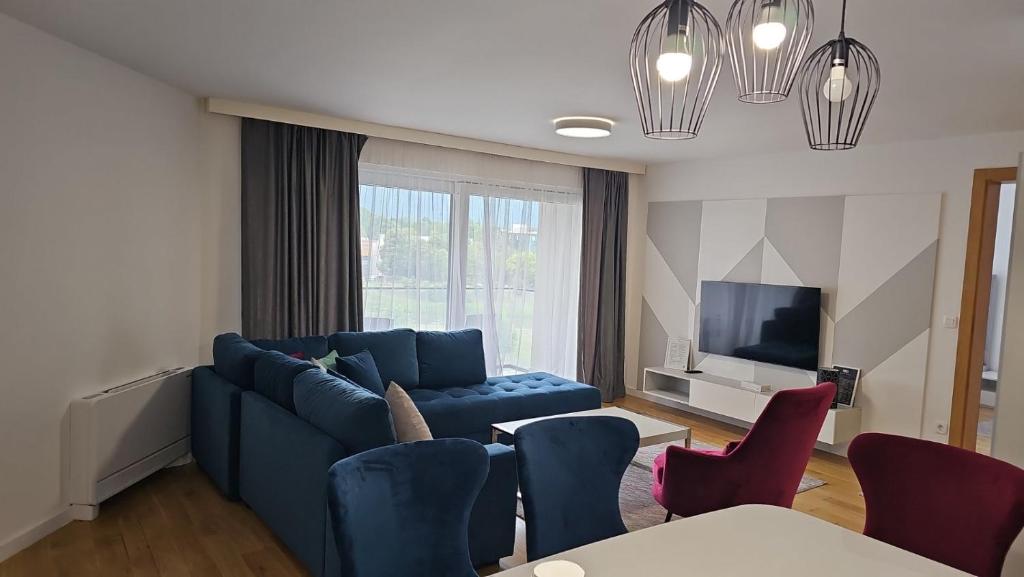 a living room with a blue couch and a tv at Orange Apartment in Sarajevo