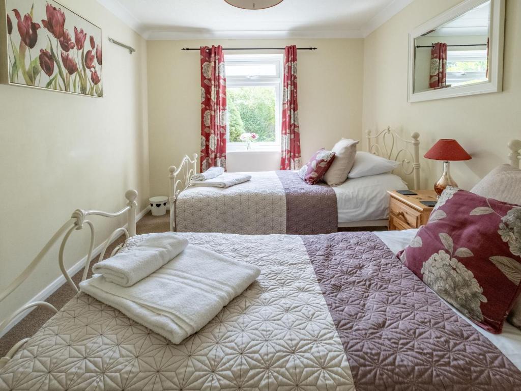 a bedroom with two beds and a window at Holiday Home Ash Cottage by Interhome in Shermanbury