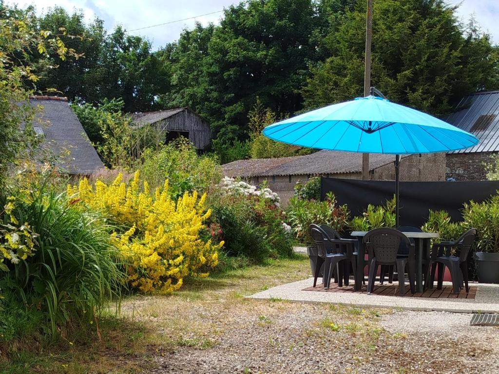 - une table et des chaises avec un parasol bleu dans le jardin dans l'établissement LE GITE Valbrock, à Plouray