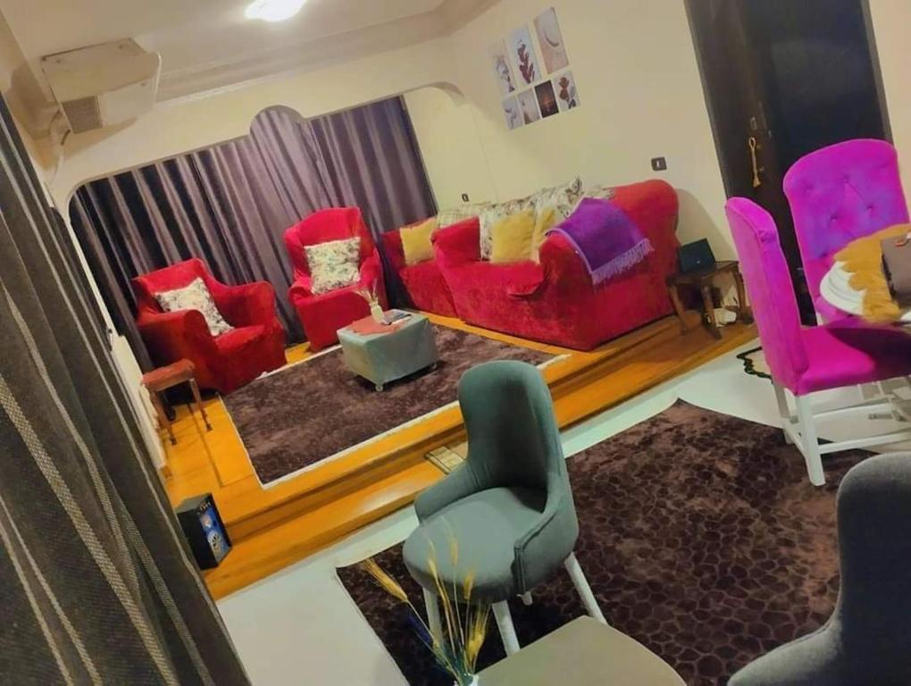 a living room with red couches and pink chairs at كورنيش النيل in Cairo