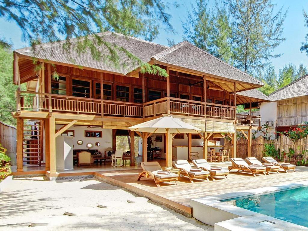 a large house with a swimming pool and a house at The Gili Beach Resort in Gili Trawangan