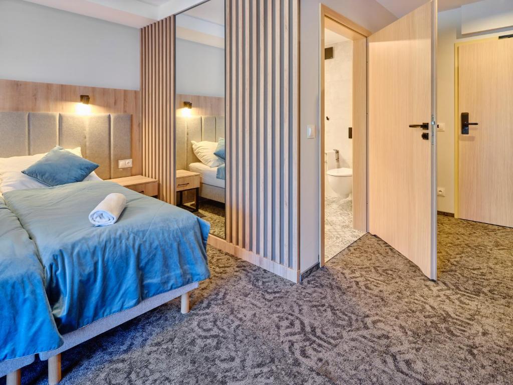 Bedroom corner with teal bed, padded headboard reflected in mirror and open bathroom door.