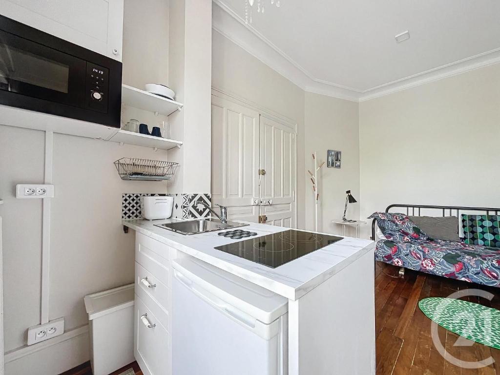 une cuisine blanche avec un évier et un micro-ondes dans l'établissement SCI Les Petits Blés, à Chartres