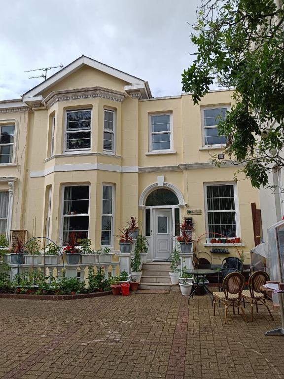 Una gran casa amarilla con un patio enfrente. en Mayville House Flat, en Cheltenham