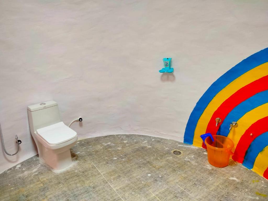 a bathroom with a toilet and a rainbow painted on the wall at Thotadha Mane A-Frame Cabin in Dodbelvangala