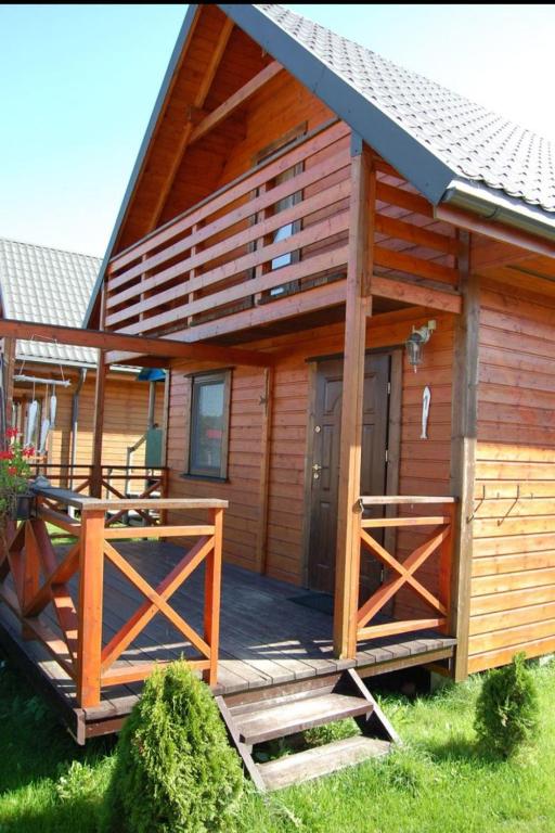 a large wooden cabin with a large deck at Domek piętrowy klimatyzowany, ogrzewany z jacuzzi na terenie ośrodka- Domki u Staszka in Rusinowo