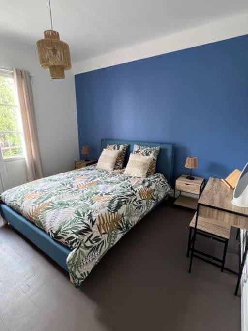 une chambre avec un lit avec un mur bleu dans l'établissement Le Vaillant appartement Cosy, à Dijon