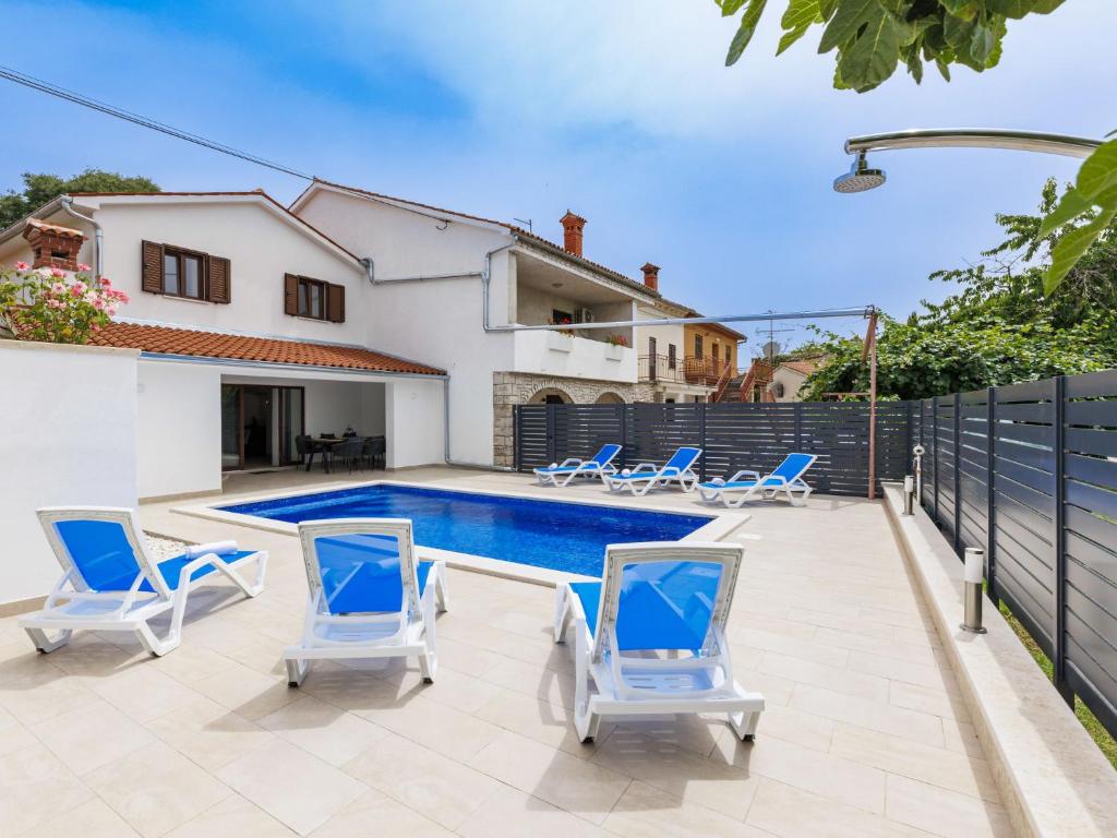 a villa with a swimming pool and blue chairs at Holiday Home Villa Marija by Interhome in Marčana