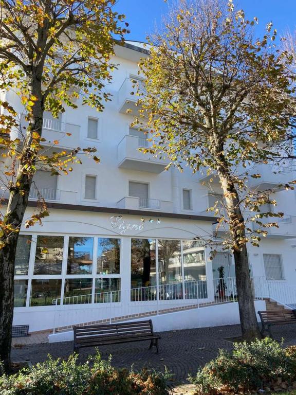 a large white building with two trees in front of it at Residence Cigno in Rimini