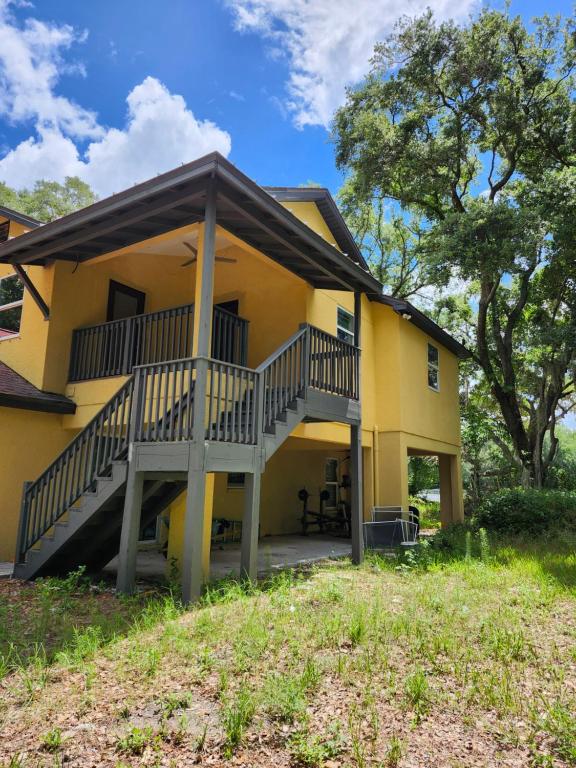 a yellow house with a staircase in front of it at la casa del bosque in Bradenton