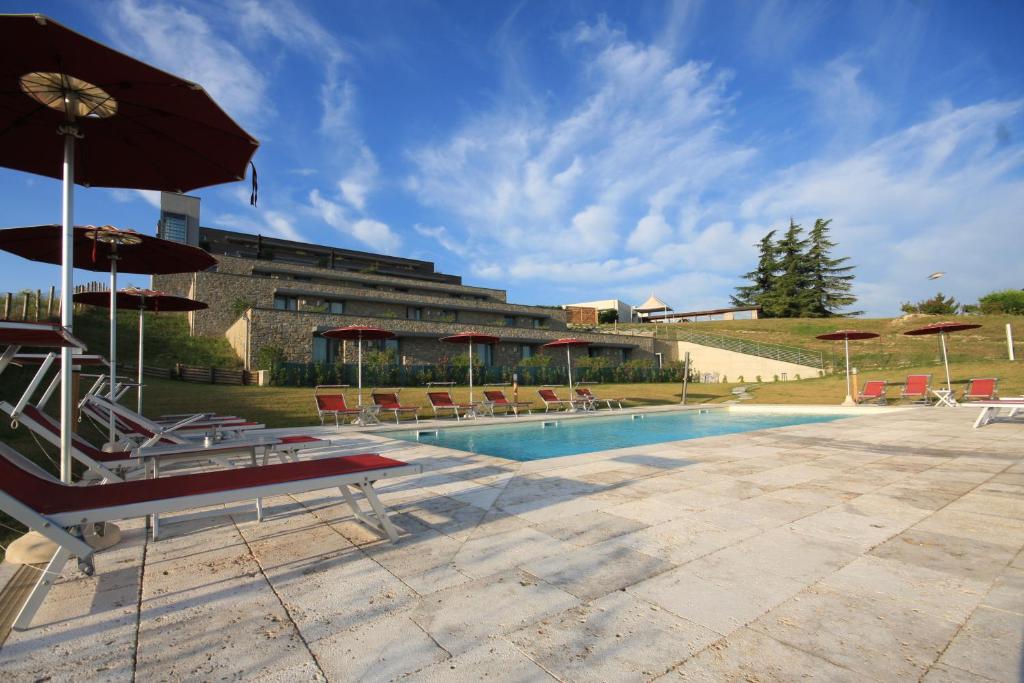 a pool with chairs and umbrellas next to a building at Ca' Del Lupo in Montelupo Albese