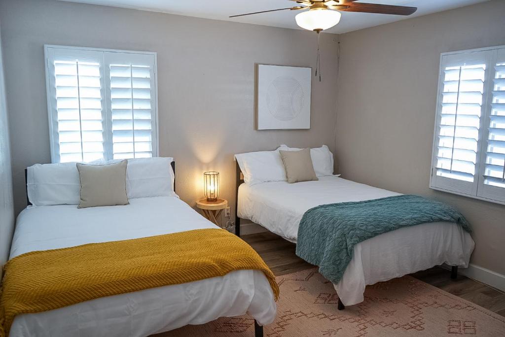 two beds in a room with two windows at The Pink Cactus - Desert Retreat - Luxe Pool, Golf & Game Room in Indio