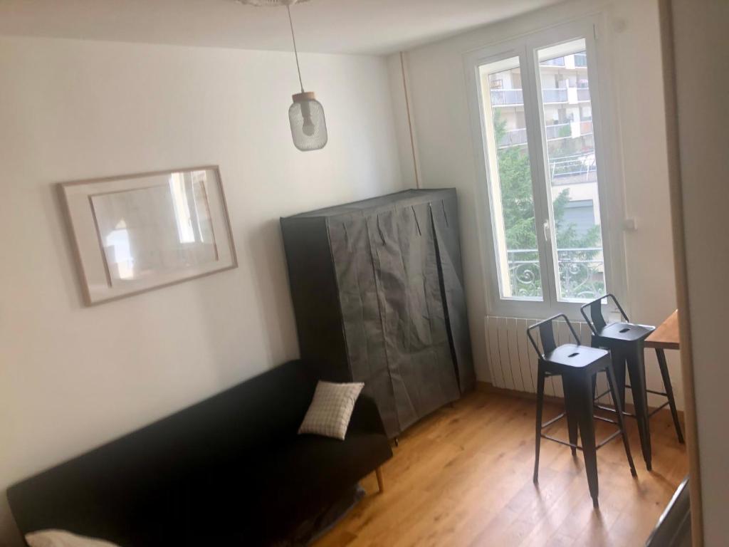 - un salon avec un canapé noir et une fenêtre dans l'établissement StudioParis20e, à Paris