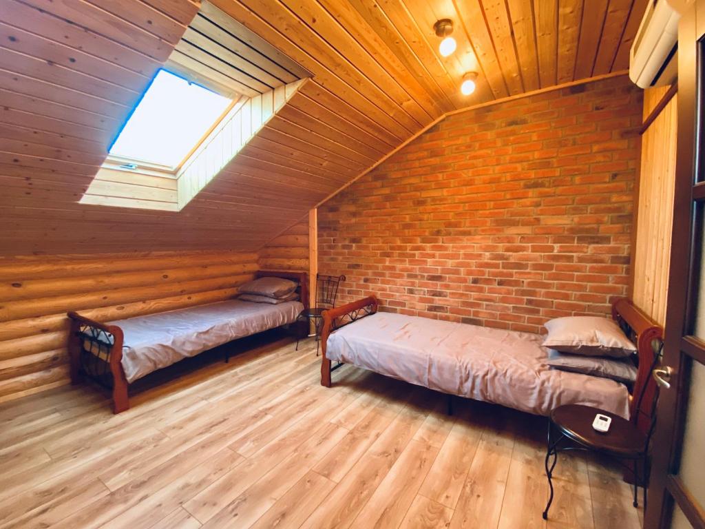 a attic room with two beds and a window at Cozy Cabins Vydmantai in Kiauleikiai