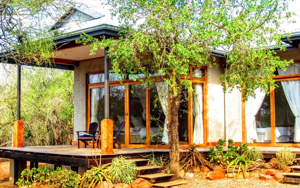 ein Haus mit einer Terrasse und einem Baum in der Unterkunft Chumbi Bush House in Hluhluwe