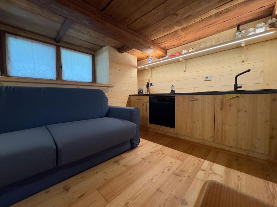 a living room with a blue couch and a kitchen at Stilish wooden chalet fully renovated near the lifts in Alagna Valsesia