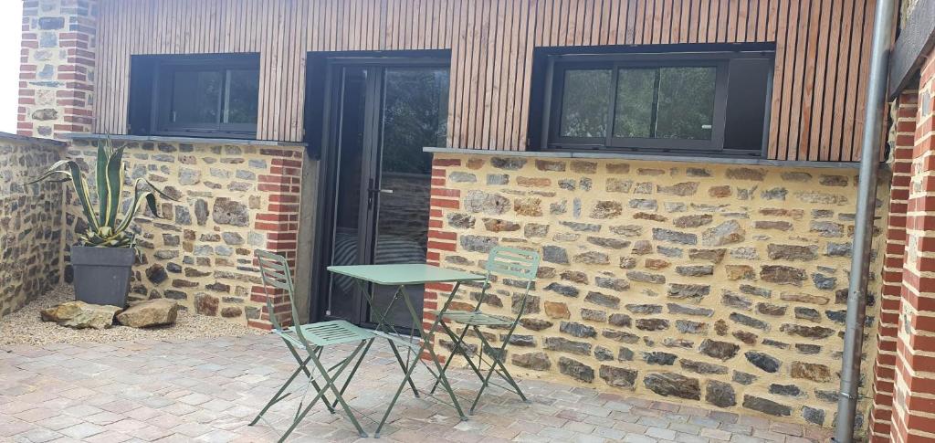 une table et des chaises devant un bâtiment en briques dans l'établissement Studio Pic au vert, à Martigné-Ferchaud