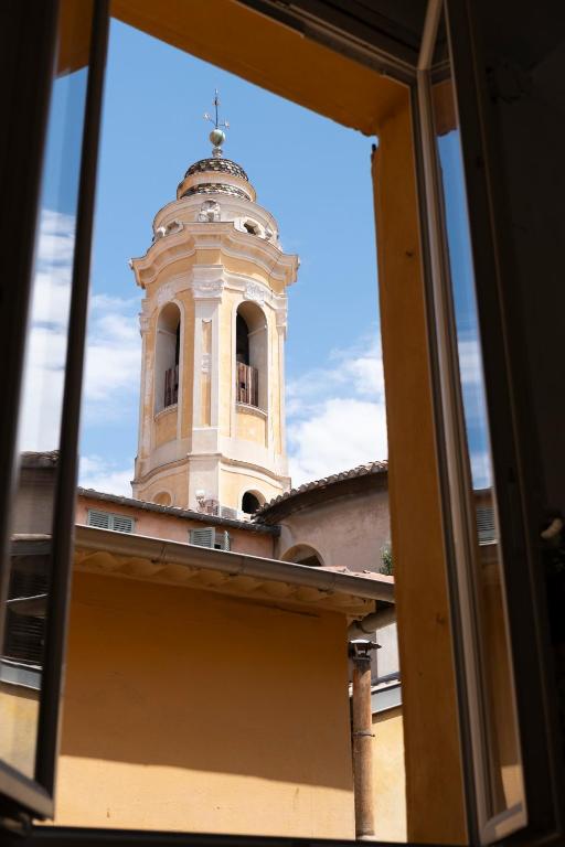 une tour d'horloge vue à travers une fenêtre d'un bâtiment dans l'établissement Appartement spacieux vieux Nice, à Nice